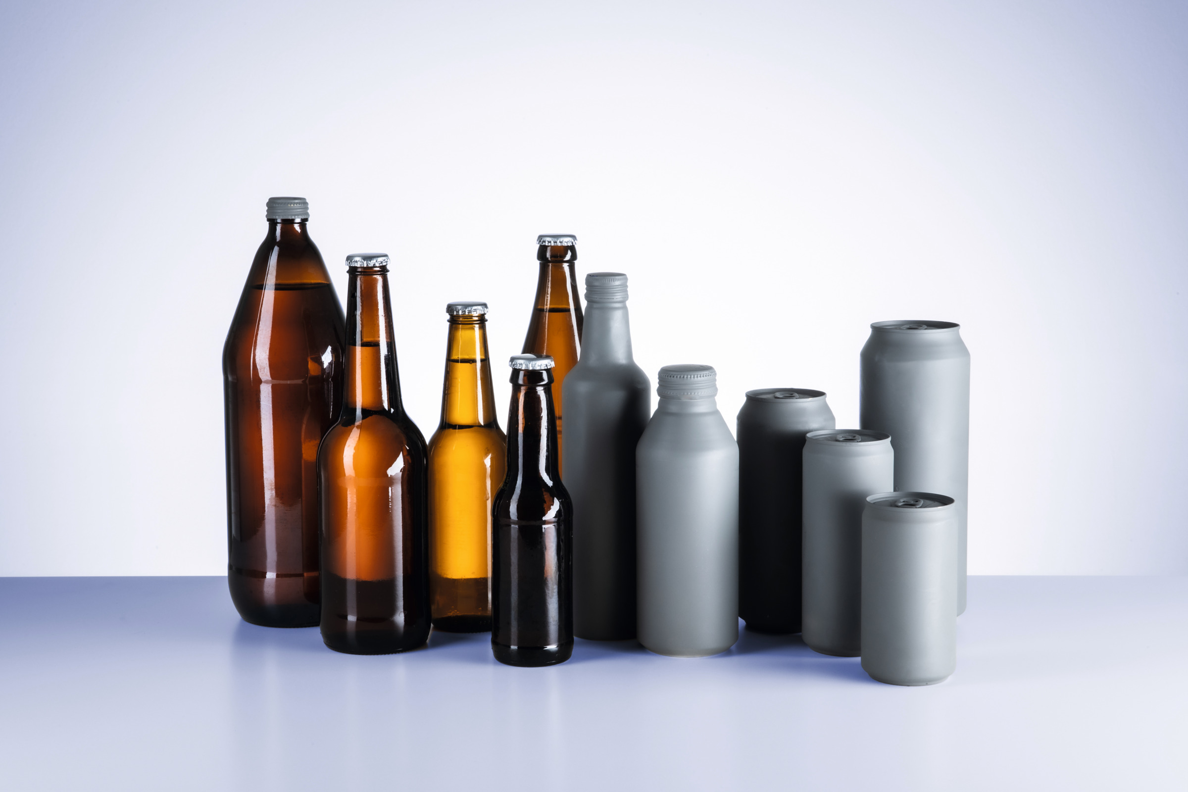 Assorted glass beer bottles and aluminum beverage cans arranged on a laboratory surface for automated container analysis with ALAB 5000