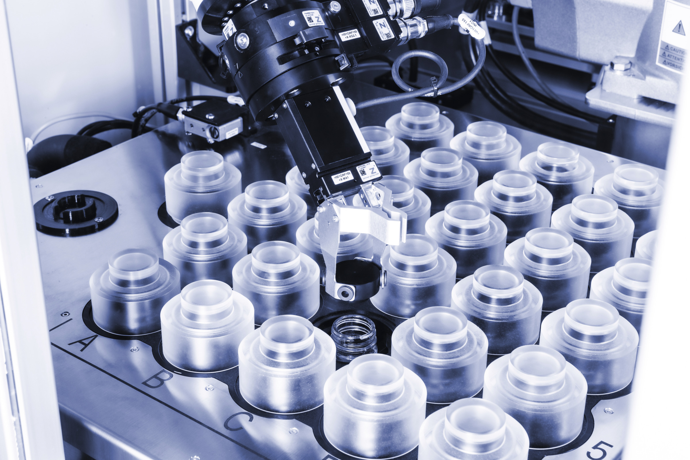 Close-up of Anton Paar HTR 7000 robotic gripper handling sample containers in an automated laboratory tray system