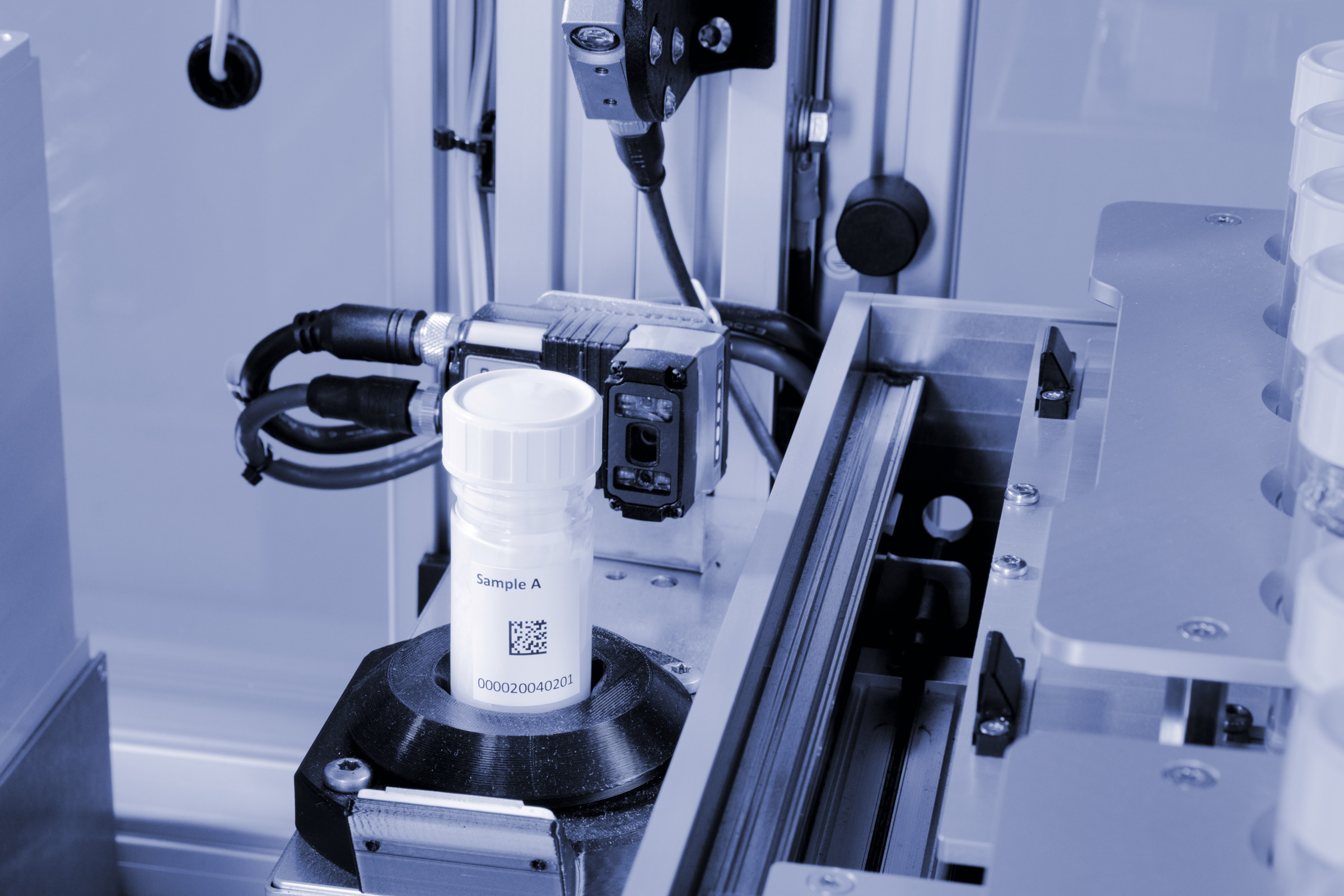 Close-up of Anton Paar HTR 7000 automated sample handling system scanning a labeled sample vial with barcode reader