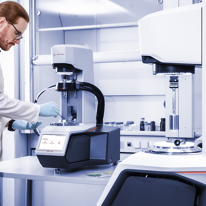 Technician adjusts an Anton Paar Modular Compact Rheometer MCR 503 with temperature accessory beside another Anton Paar rheometer