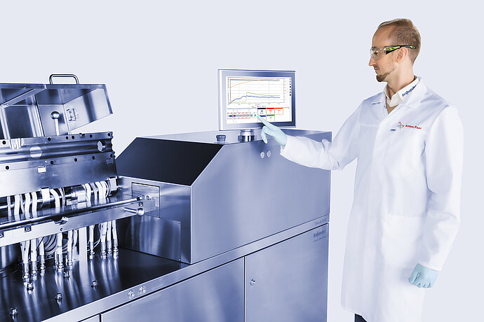 Technician operating Brabender TwinLab B-TSE-S-30-40 twin-screw extruder, adjusting touchscreen while process section with piping is open