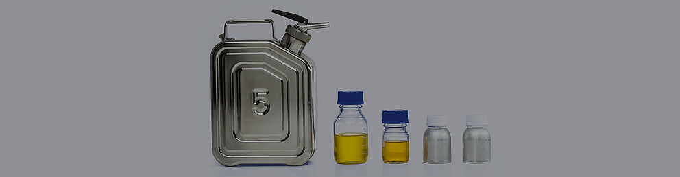 Black fuel nozzle beside three red-capped glass sample tubes containing clear and pale-yellow diesel samples.