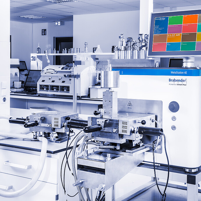 Brabender MetaStation 4E modular torque rheometer with two front test attachments and MetaBridge touchscreen in a laboratory beside sample containers.
