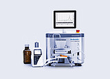 Brabender AbsorptoMeter with hopper and integrated display showing measurement curves, connected via tubing to a dosing unit and reagent bottle on a lab bench