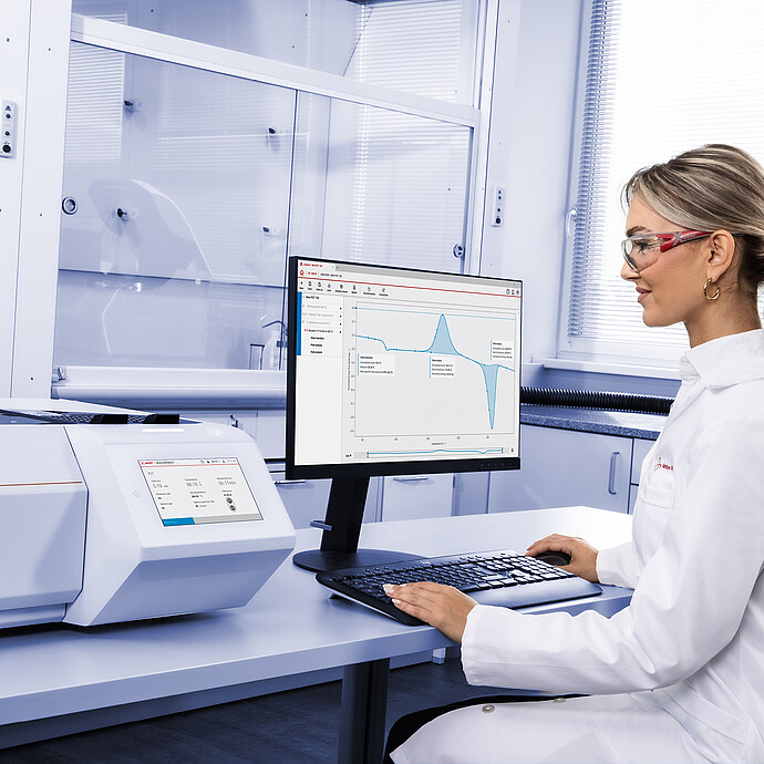 Technician operating Anton Paar Julia DSC 300 in laboratory, using Julia Suite on monitor displaying DSC measurement curve, with additional instrument in background