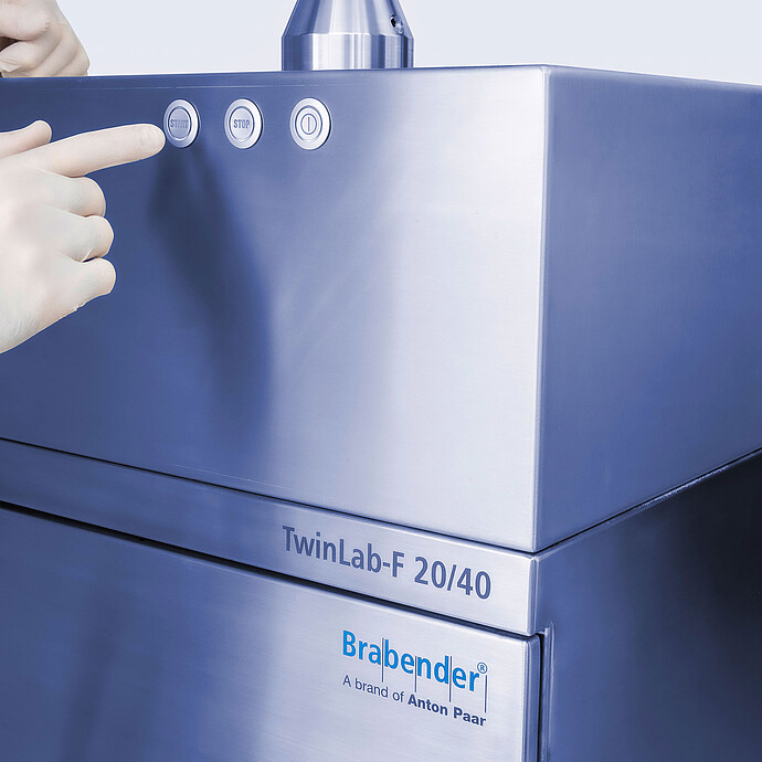 TwinLab Series Brabender TwinLab-F 20/40 laboratory extruder, close-up with gloved technician pressing START.