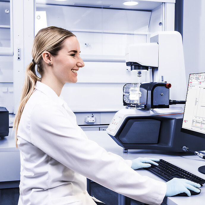 Technician using RheoCompass software beside two Anton Paar Modular Compact Rheometer MCR instruments in a lab