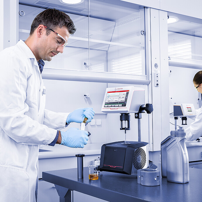 Laboratory staff preparing lubricant samples beside the ViscoQC ASTM D2983 system for low-temperature viscosity testing.