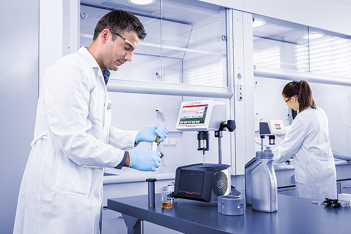 Laboratory staff preparing lubricant samples beside the ViscoQC ASTM D2983 system for low-temperature viscosity testing.