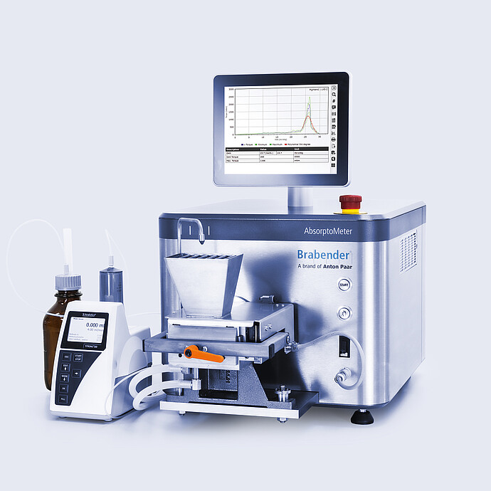 Brabender AbsorptoMeter with open hopper and measuring chamber, integrated display showing torque curve, connected via tubing to dosing unit and reagent bottle on lab bench