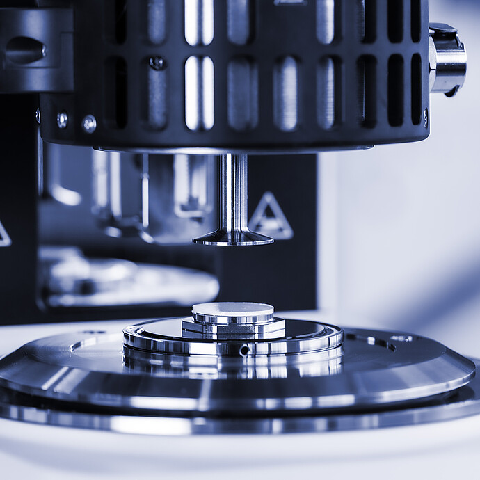 Close-up of the measuring geometry above a polymer sample on the plate of an Anton Paar SmartMelt polymer melt rheometer.