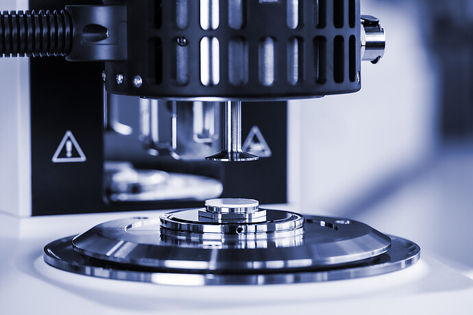 Close-up of the measuring geometry above a polymer sample on the plate of an Anton Paar SmartMelt polymer melt rheometer.