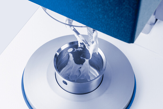 Close-up of the Brabender GlutoPeak mixing chamber during gluten analysis, showing dough-like sample being processed by the rotor blade.