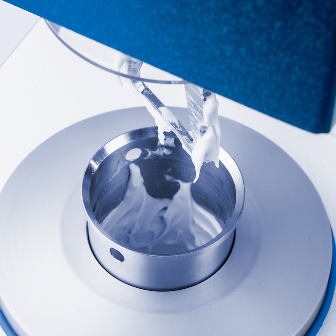 Close-up of the Brabender GlutoPeak mixing chamber during gluten analysis, showing dough-like sample being processed by the rotor blade.