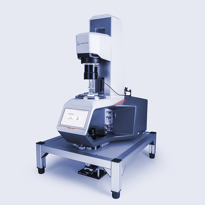 Anton Paar MCR 703 rheometer equipped with the Rheo-Iris optical accessory, mounted on a vibration-damping table with active touchscreen display.