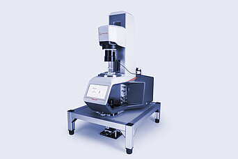 Anton Paar MCR 703 rheometer equipped with the Rheo-Iris optical accessory, mounted on a vibration-damping table with active touchscreen display.