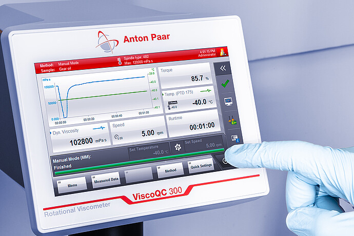 Angled close-up of the ViscoQC 300 touchscreen as a gloved hand taps the interface, showing a gear oil test and PTD 175 temperature at −40.0 °C