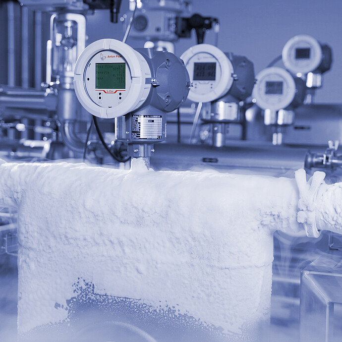 Anton Paar L-Cor 8000 Coriolis flow meter with display mounted on frost-covered stainless steel piping in a cold industrial processing environment.