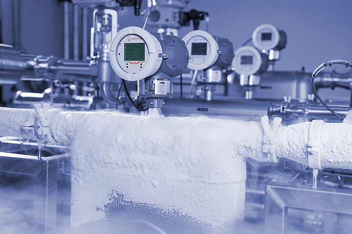 Anton Paar L-Cor 8000 Coriolis flow meter with display mounted on frost-covered stainless steel piping in a cold industrial processing environment.