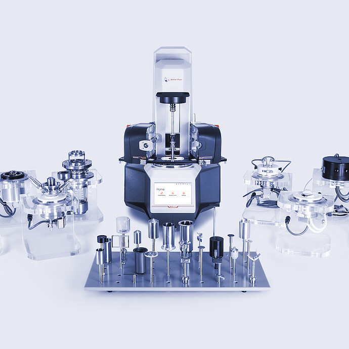 Anton Paar Modular Compact Rheometer MCR with accessory modules and measuring geometries arranged on a studio surface