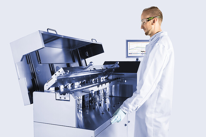 Technician operating Brabender TwinLab B-TSE-S-30-40 twin-screw extruder with open process section, inspecting internal modules and piping