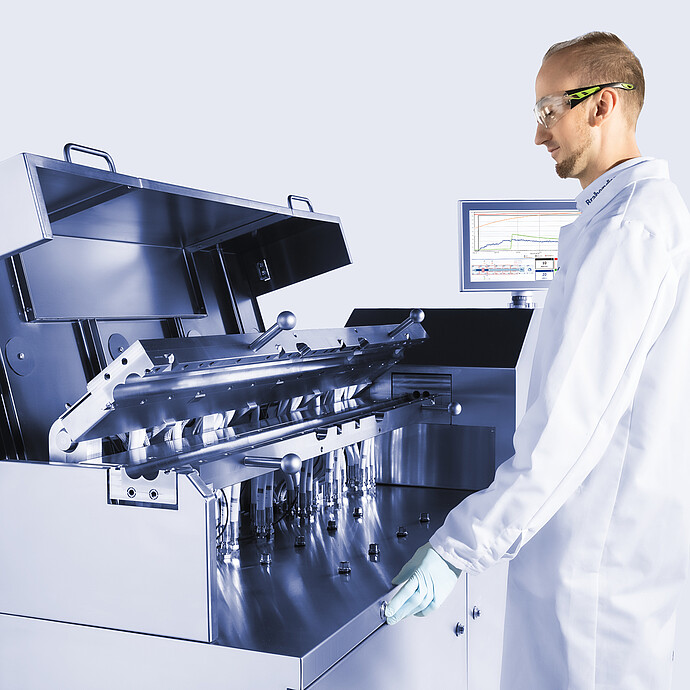 Technician operating Brabender TwinLab B-TSE-S-30-40 twin-screw extruder with open process section, inspecting internal modules and piping