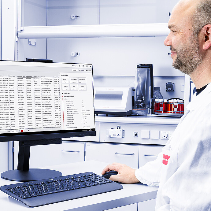 Technician using AP Connect on a monitor, with Anton Paar RTD Measurement System and red sample vials in the lab background.