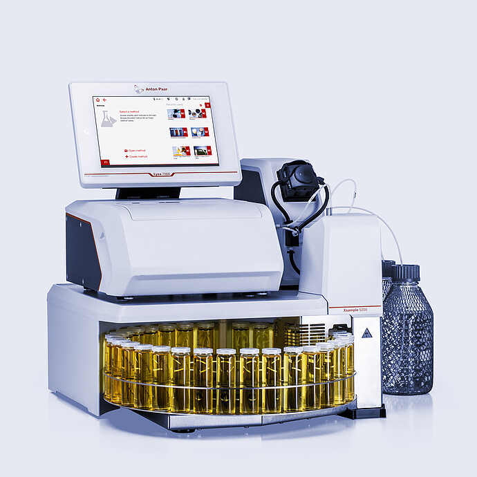 Anton Paar Lyza 7000 FTIR spectrometer with Xsample 5200 autosampler, tubing, and a carousel of yellow liquid sample vials.
