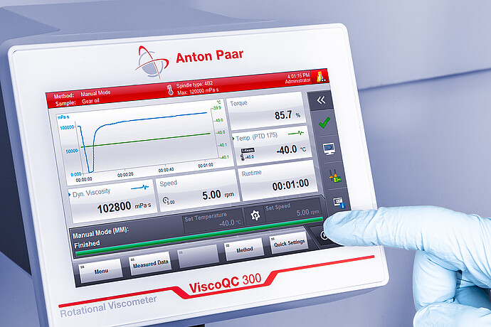 Angled close-up of the ViscoQC 300 touchscreen as a gloved finger taps Start, showing a gear oil test with spindle type 4B2 and PTD 175 temperature at −40.0 °C on a light blue background