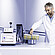 Lab technician handling vial carousel beside Anton Paar DMA 5002 with Lovis 2000 M/ME and Xsample 530 sample changer