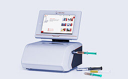Anton Paar Lyza 7000 FTIR spectrometer with touchscreen, connected flow cell, and several syringes on a light gray background.