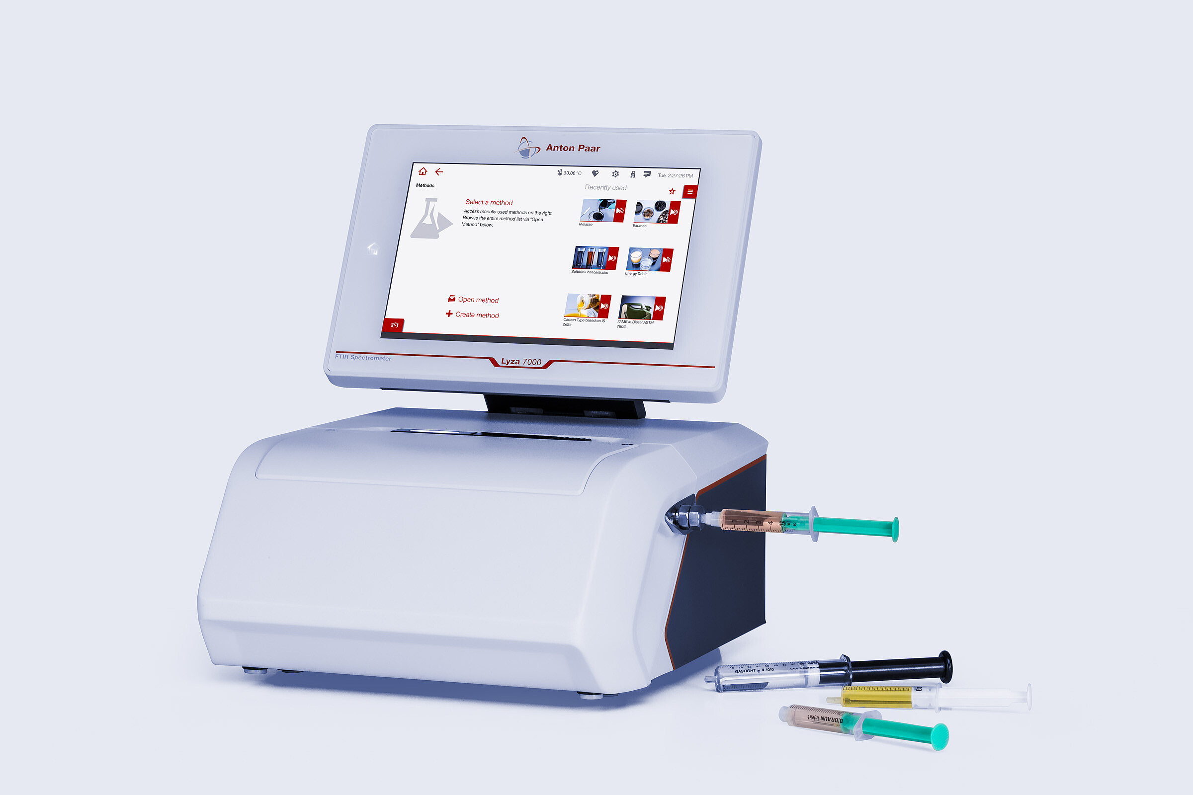 Anton Paar Lyza 7000 FTIR spectrometer with touchscreen, connected flow cell, and several syringes on a light gray background.