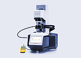 Anton Paar SmartPave 303 rheometer with connected temperature-control hoses and a handheld digital meter on a light background.