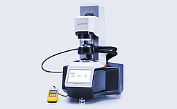 Anton Paar SmartPave 303 rheometer with connected temperature-control hoses and a handheld digital meter on a light background.