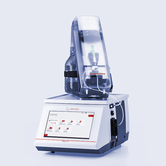 Anton Paar DMA 5002 density meter with Xsample 340 sample changer mounted on top, clear cover, syringe, tubing, and bottle