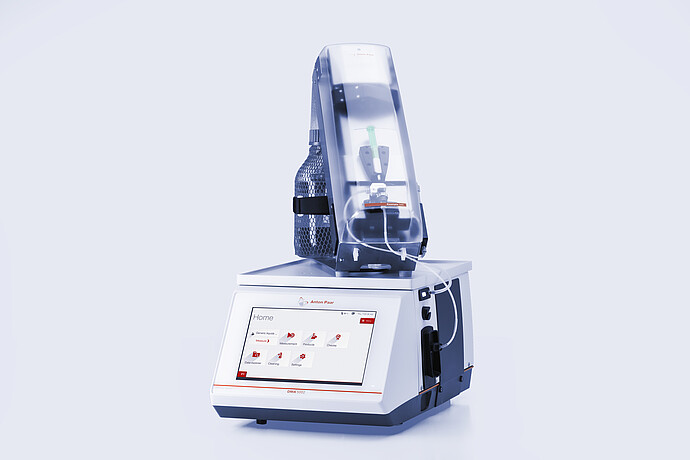 Anton Paar DMA 5002 density meter with Xsample 340 sample changer mounted on top, clear cover, syringe, tubing, and bottle