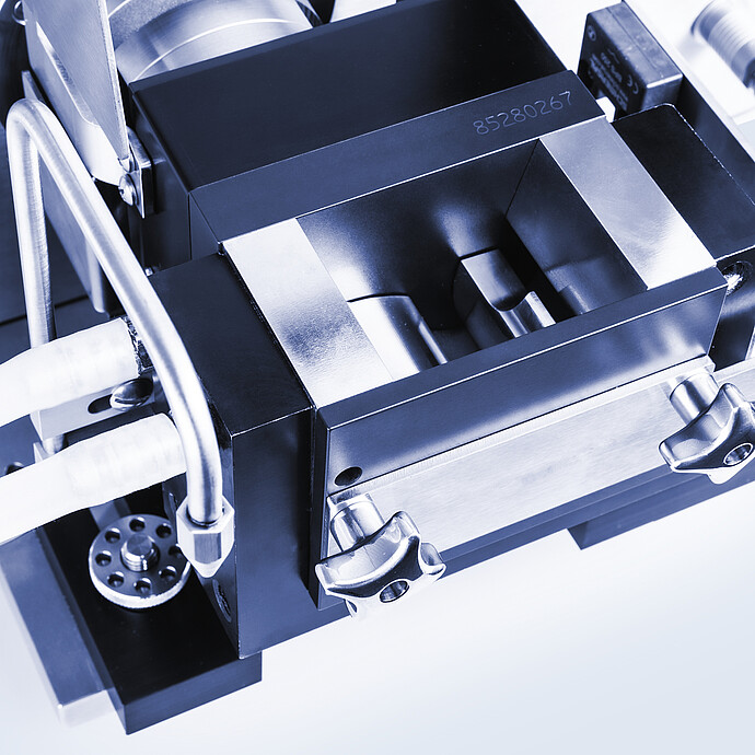 Close-up of Brabender AbsorptoMeter measuring chamber with open mixing bowl, visible sigma blades, metal housing, and locking screws