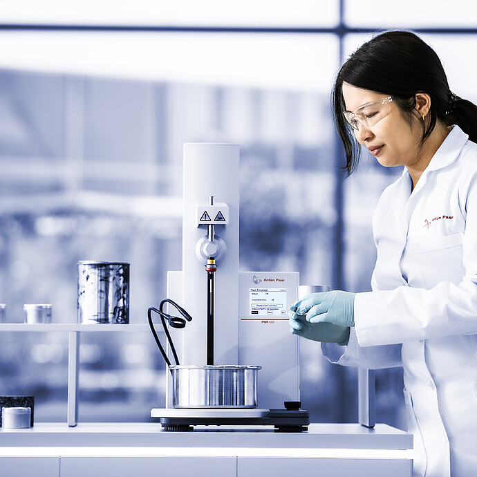 Technician operating Anton Paar Penetrometer PNR 500 in a laboratory, preparing metal sample cup for penetration measurement.