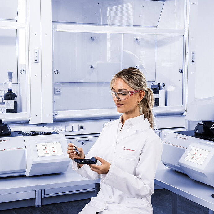 Technician holding sample tray and crucible in laboratory with Anton Paar Julia DSC 300 and Julia DSC 500, both with integrated touchscreens