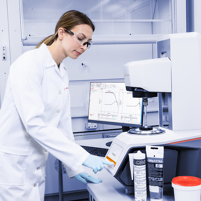 Lab technician in safety glasses operating an Anton Paar Modular Compact Rheometer MCR on a laboratory bench