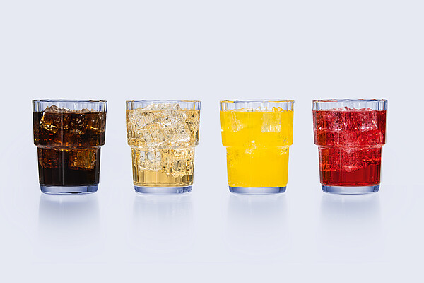 Four glasses with ice containing non-alcoholic and low-alcohol beer samples in varying colors, arranged side by side against a light background