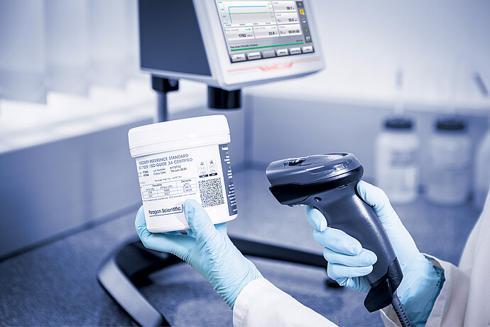 Operator scanning a viscosity reference standard beside the ViscoQC ASTM D2983 system for calibration and traceable testing.