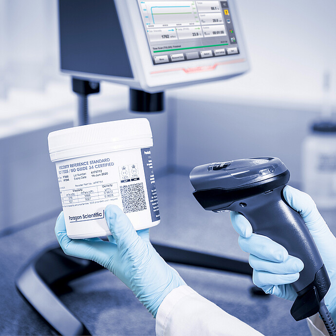 Operator scanning a viscosity reference standard beside the ViscoQC ASTM D2983 system for calibration and traceable testing.