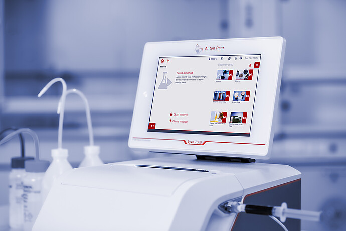 Close-up of the Anton Paar Lyza 7000 FTIR spectrometer with method menu on the touchscreen and a syringe connected to the flow cell.