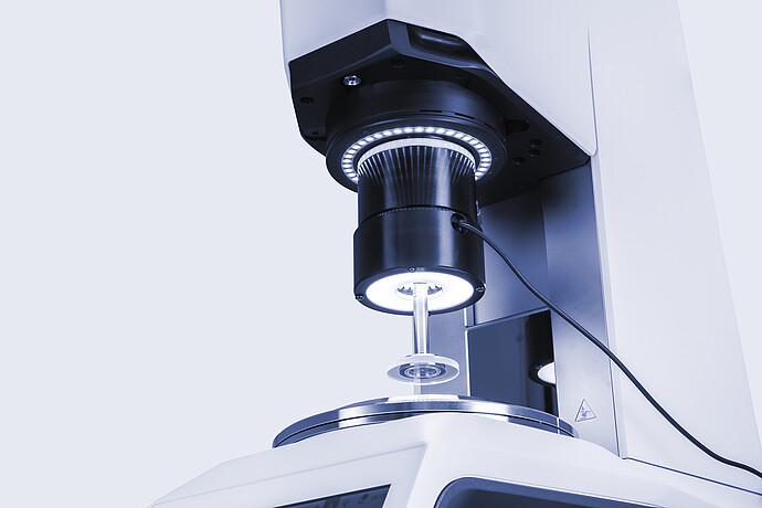 Close-up of the Rheo-Iris optical accessory mounted on an Anton Paar MCR rheometer, with illuminated sample geometry during measurement.