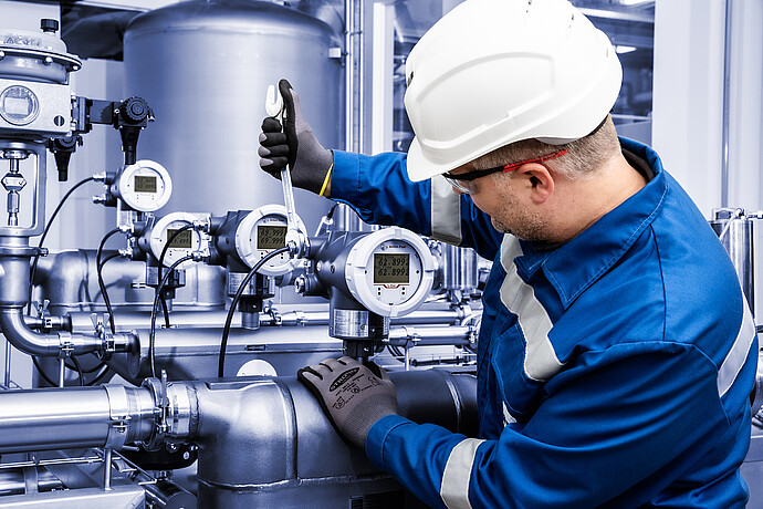 Technician using a wrench to install L-Cor 8500 Coriolis flow meter on industrial pipeline with multiple L-Cor 8500 transmitters and gauges