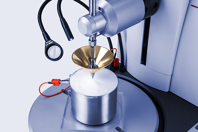 Close-up of Anton Paar Penetrometer PNR 500 with brass cone penetrating white semisolid sample in metal cup, with temperature sensor attached.