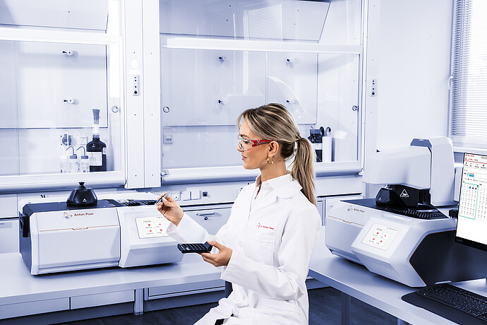 Technician handling sample tray beside Anton Paar Julia DSC 300 and second Julia DSC instrument, with Julia Suite displayed on monitor in laboratory setting