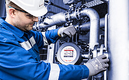 Industrial technician servicing an Anton Paar L-Dens inline density sensor on a stainless steel pipeline in a processing facility.