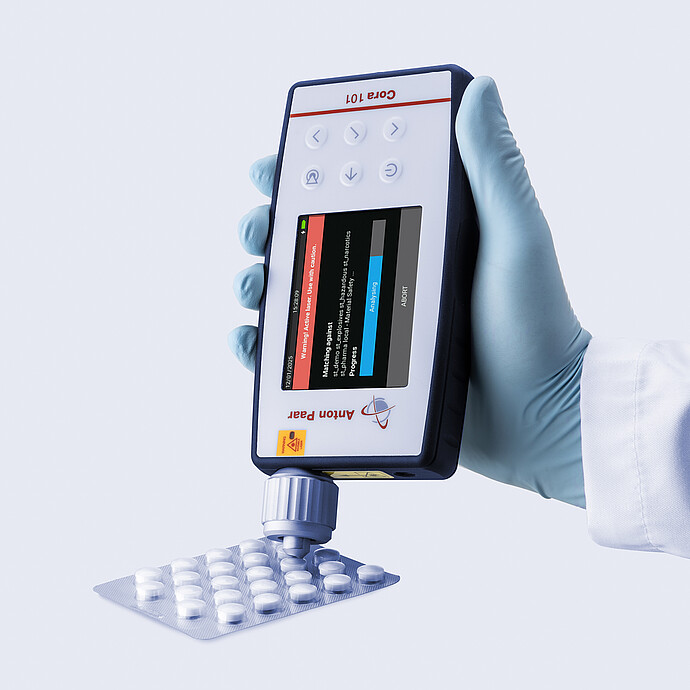 Gloved hand using the Anton Paar Cora 101 handheld Raman spectrometer to analyze tablets in a blister pack.